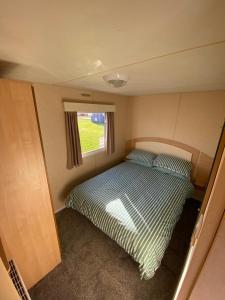 a small bedroom with a bed in a trailer at 8 Berth Holiday Home with Pools on Martello Beach in Jaywick Sands