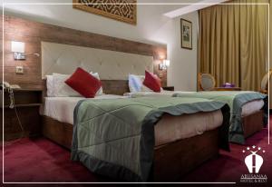 una camera d'albergo con due letti con cuscini verdi e rossi di Abu Sanaa Hotel a As Sulaymānīyah