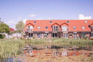 una casa grande con un estanque frente a ella en "Haus am Teich" Haus am Teich, Whg 2, en Büsum