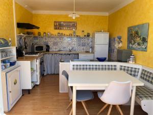 a kitchen with yellow walls and a table and chairs at Ty Mimi in Plozévet