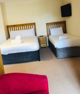 a room with two beds and a red couch at Canons Court Mews in Wotton under Edge