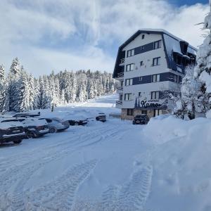 a building in the snow with cars parked next to it at Cozy Ski Apartment Jahorina in Jahorina