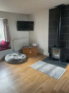 a living room with a fireplace and a bed at Cotswold Coombe Cottage in Wotton-under-Edge