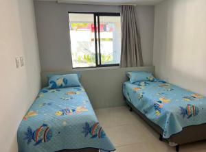a bedroom with two beds and a window at Itacimirim pé na areia 2Q in Itacimirim