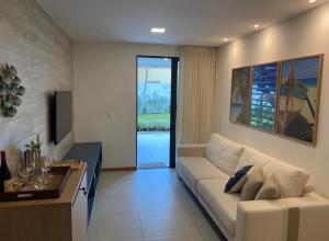 ein Wohnzimmer mit einem weißen Sofa und einem TV in der Unterkunft Itacimirim pé na areia 2Q in Itacimirim