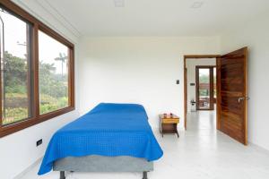 1 dormitorio con cama azul y ventana grande en Casa de Ensueño. Pedro Vicente Maldonado., en Pedro Vicente Maldonado