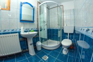 a blue tiled bathroom with a toilet and a sink at Kamilla Vendégház Borzont in Borzont