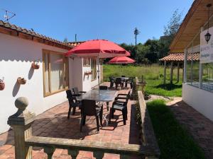 eine Terrasse mit einem Tisch, Stühlen und roten Sonnenschirmen in der Unterkunft Paipa de ensueño en casa Sochaloma in Paipa