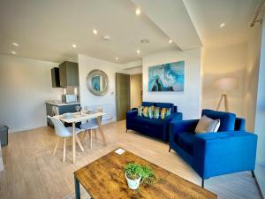 a living room with a blue couch and a table at Serviced Apartments Nailsea in Nailsea