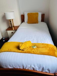 Una cama blanca con una manta amarilla. en Blessed Roker home with free parking., en Monkwearmouth