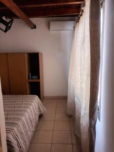 1 dormitorio con cama y cortina blanca en Departamento Zanzin en Mendoza