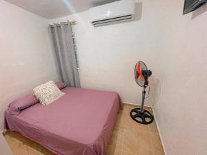 Dormitorio pequeño con cama rosa y ventilador en Acogedora casa de 2 habitaciones, en Villa Isabela