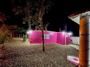 Acogedora casa de 2 habitaciones في Villa Isabela: مبنى وردي امامه شجرة