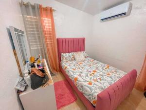 a small bedroom with a pink bed and a table at Acogedora casa de 2 habitaciones in Villa Isabela