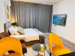 a bedroom with a bed and chairs and a tv at Home in Abu Dhabi