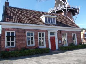 un bâtiment en briques rouges avec un moulin à vent en haut dans l'établissement Zeer sfeervol gastenverblijf in Het Molenhuisje met woonkamer en keuken, à Winschoten