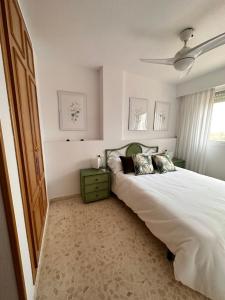 Un dormitorio con una gran cama blanca y una ventana en Precioso apartamento con piscina, en Playa de Gandía