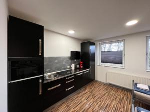 a black kitchen with a sink and a window at Appartments Casa del Sol in Braunschweig