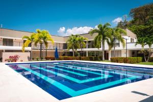 una piscina frente a un edificio con palmeras en Villa California, en Sopetrán