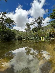 un cuerpo de agua con árboles y un cielo nublado en Vale da Vacaria, en Serra do Cipo