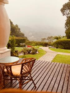 una terraza de madera con mesa y silla en Pousada Brisa da Mantiqueira en Monte Verde