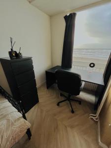 a bedroom with a desk and a window with the beach at Apartment Marmoris in Zandvoort