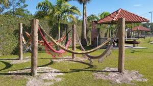 a hammock in a park with a bench and palm trees at Kitnet Apartamento Praia Matinhos in Matinhos