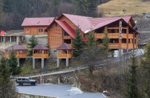 a wooden house with a car parked in front of it at ВІДЕНЬ in Slavske