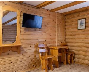 a log cabin with a table and a tv on a wall at ВІДЕНЬ in Slavske