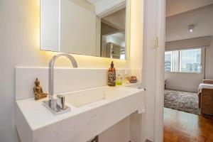 Baño blanco con lavabo y espejo en Apartamento charmoso próx à Av Paulista, en São Paulo