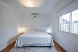 Habitación blanca con cama y ventana en Apartamento charmoso próx à Av Paulista, en São Paulo