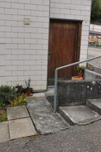 um conjunto de escadas que levam a um edifício com uma porta de madeira em Schönes kleines Studio mit Sitzplatz, mitten im Prättigau em Jenaz