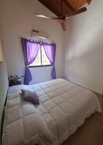 um quarto com uma grande cama branca com cortinas roxas em Luz de Luna Ubicación privilegiada frente a laguna y piscina em San Cosme