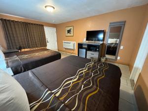 a hotel room with two beds and a flat screen tv at New Corral Motel in Victorville