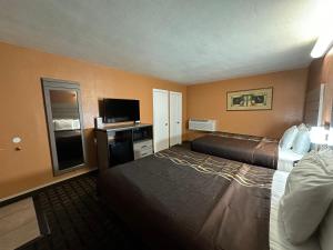 a hotel room with two beds and a flat screen tv at New Corral Motel in Victorville