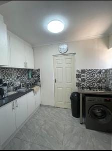 a kitchen with a white door and a clock on the wall at Tia Maria cottage in Cape Town