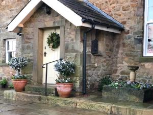 a stone house with potted plants in front of it at Picket Post House Bed & Breakfast in Catterall
