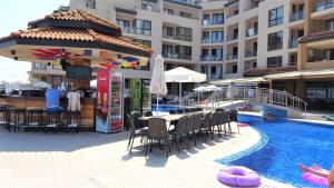 una piscina con mesa y sillas junto a un edificio en Seafront Apartment im Obzor Beach Resort en Obzor