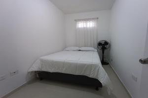a white bedroom with a bed and a window at Ayenda Brisas del Rio in Barranquilla