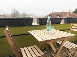 a wooden table with a bottle and two chairs on a balcony at LIME HOMES: Balkon, Küche, Netflix in Barsinghausen