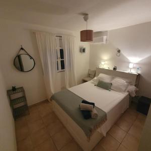 ル・ヴォクランにあるCHARMANT HAUT DE VILLA AVEC PISCINE PARTAGEEのベッドルーム(鏡付きの大きな白いベッド1台付)
