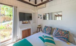 因比圖巴的住宿－Casa Natureza Praia do Rosa，一间卧室设有一张床、一台电视和一个窗口。