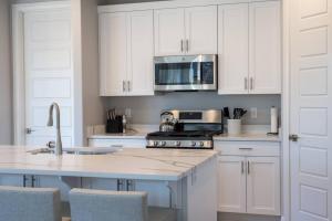 une cuisine avec des armoires blanches, un évier et un micro-ondes dans l'établissement Cozy Sweet Retreat Brand New Private Home w Spa Game Room and Firepit, à Washington