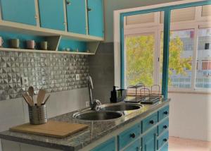 um balcão de cozinha com um lavatório e uma janela em AtelierSurf29 Guest House em Almada