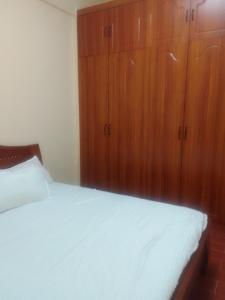 a bedroom with a white bed and wooden cabinets at Smarts residence in Nairobi