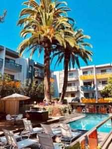 a pool with chairs and palm trees in a hotel at Charming Hollywood Condo with Pool & Balcony in Los Angeles