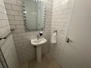 a white bathroom with a sink and a mirror at 2br aptSurrounded by history with Modern Amenities in Panama City
