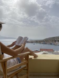 a woman sitting in a chair reading a book at Marina Castellana Studios in Halki