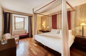 a hotel room with a bed with a canopy at NH Collection Palacio de Burgos in Burgos