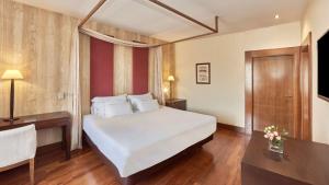 a bedroom with a large white bed and a desk at NH Collection Palacio de Burgos in Burgos